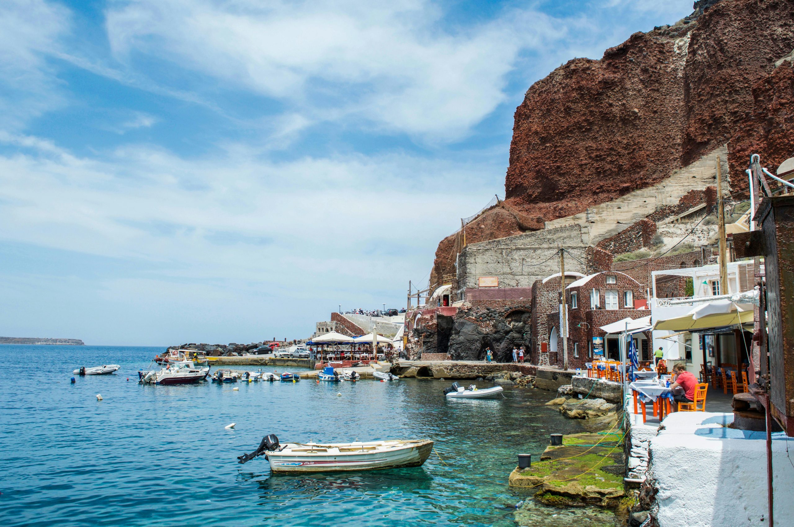 Picturesque view of Santorini's harbor with boats and iconic architecture.