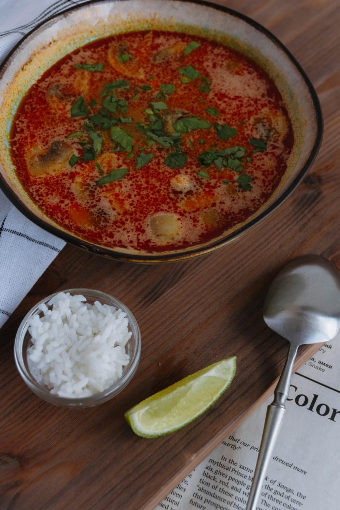 Delicious spicy Thai soup with fresh lime and rice, presented beautifully on a rustic table.