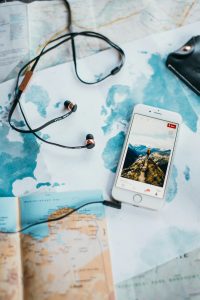 Flatlay of travel essentials including map, smartphone, and earphones for wanderlust inspiration.